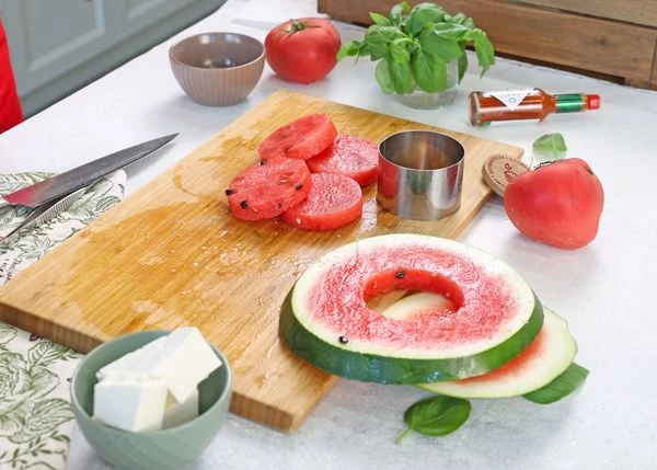 Арбуз вымыть, нарезать на ломтики. Из мякоти вырезать кружочки по размеру томатов.