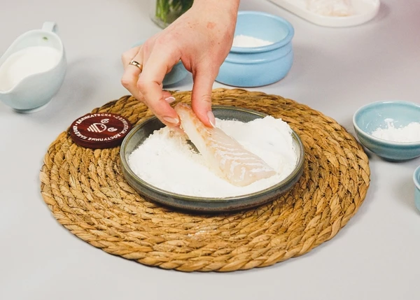 Филе трески разморозить на нижней полке холодильника. Муку смешать с крахмалом и солью. Обвалять в этой смеси кусочки трески.