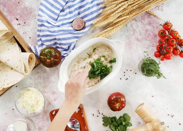 В натертый лук добавить фарш кальмара, соль, перец и нарезанную кинзу, перемешать.