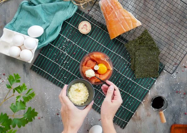 Филе горбуши разморозить на нижней полке холодильника, удалить кожу, нарезать на кусочки, выложить в чашу блендера. Добавить соль, желток и натертый сыр.