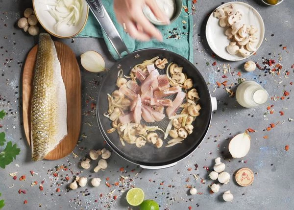 Филе разморозить на нижней полке холодильника, снять с кожи, нарезать ломтиками. Затем добавить у луку и грибам, обжаривать пару минут.