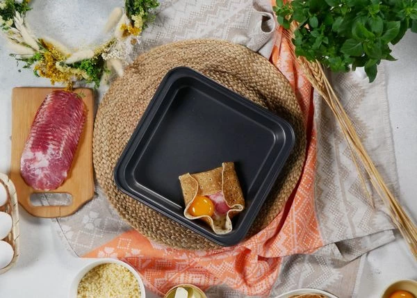 Затем выложить ветчину и желток. Посолить и поперчить. Подогнуть края, чтобы получился квадрат. 