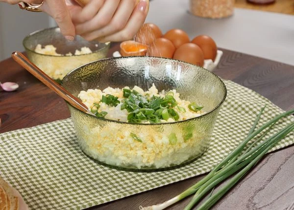 Яйца отварить вкрутую, почистить, нарезать кубиком. Отварной рис смешать с яйцами и зеленым луком, посолить, поперчить, хорошо перемешать. 
