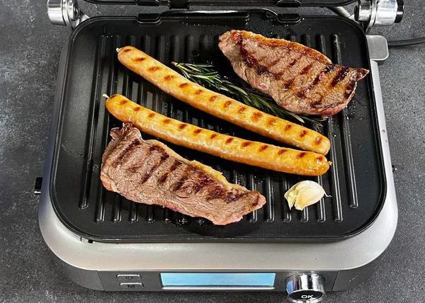 Стейки и колбаски обжарить на гриле с добавлением масла, розмарина и чеснока.