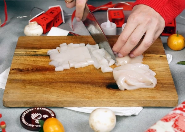 Кальмары разморозить на нижней полке холодильника. Нарезать кольцами. 