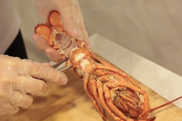 Осторожно оторвите клешни, в местах, где они соединяются с телом.Потом аккуратно оттяните нижнюю часть клешни. Подвигайте ее в разные стороны и по чуть чуть тяните. Мясо должно красиво остаться в нижней части клешни. Возьмите большой кухонный нож и ударьте обратной стороной ножа по клешне, чтобы она раскололась на 2 части. Выньте мясо.    Отсоедините так называемую "руку" от клешни. Засуньте конец ножниц вовнутрь и сделайте надрез по всей длине. Такой же надрез сделайте и на другой стороне клешни, чтобы легко ее разделить.