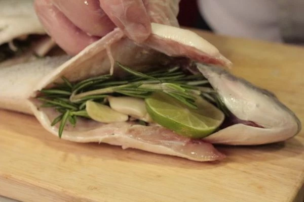 Внутрь положить несколько веточек розмарина, пару долек раздавленного чеснока, кружочки лайма