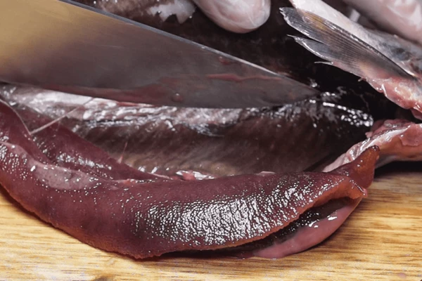 Удалить голову, зачистить от темной пленки. (Если планируете солить селедку целиком, то голову можно оставить, но обязательно необходимо вырезать жабры)