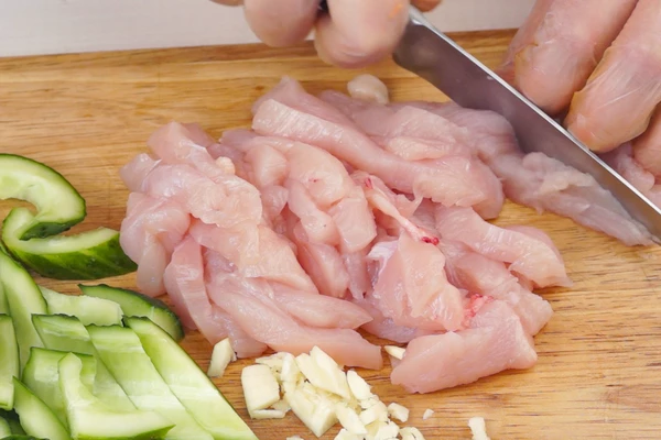 Огурцы разрезать вдоль пополам и удалить семенную коробку, нарезать брусками. Куриное филе нарезать крупной соломкой, чеснок мелко порубить. 