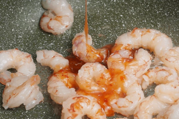  В этой же сковороде обжарить размороженные и очищенные креветки в течение 1-2 минут до розового цвета. Влить соус чили и прогреть до готовности морепродуктов 1-2 минуты. 