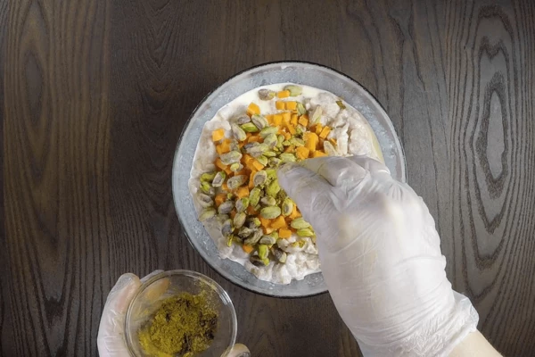 Добавить морковь нарезанную кубиком 0,6х0,6см, очищенные фисташки. Посолить, поперчить, довести до вкуса специями. Фарш перемешать и отставить в сторону.