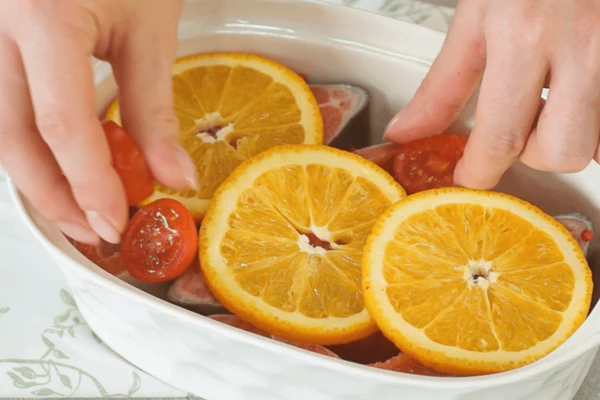 На стейки уложить кружочки апельсина и томаты.