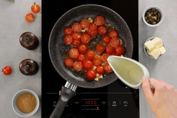 В сковороду налить оливковое масло, выложить томаты, слегка обжарить, влить вино, выпарить наполовину, выдавить сок мандарина, добавить каперсы, сахар, соль.