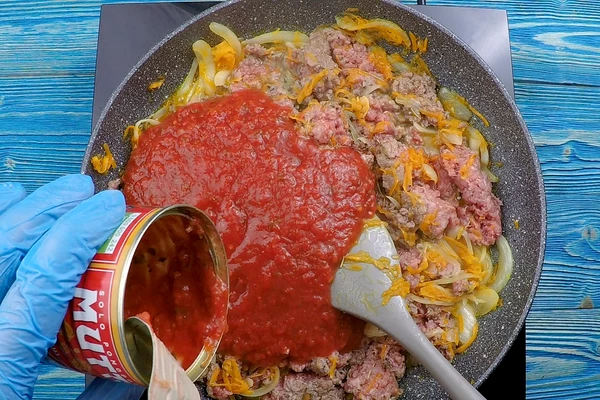 Затем добавить томаты в собственном соку, соль, перец, убавить огонь и потушить до готовности фарша.