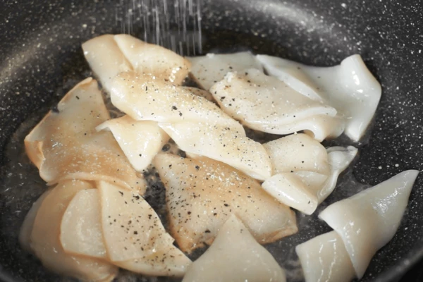 Обжарить кальмара с добавлением оливкового масла, соли и черного молотого перца. 
