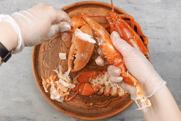 У большой клешни аккуратно оттяните нижнюю часть. Подвигайте ее в разные стороны и по чуть-чуть потяните. Мясо должно красиво остаться в нижней части клешни. Возьмите большой кухонный нож и ударьте обратной стороной ножа по клешне, чтобы она раскололась на две части. Выньте мясо.