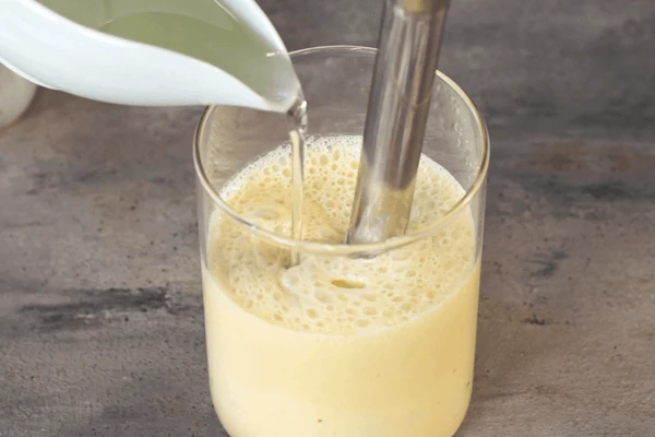 Затем влить подсолнечное масло, продолжая взбивать. Должен получиться густой соус.