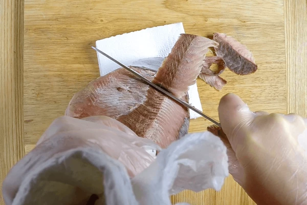 Дальше, вооружившись острым ножом, начинаем срезать тонкие пласты филе от хвоста к голове. Желательно одним движением, чтобы получилась крупная «стружка».