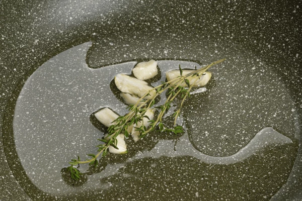 Разогреть на сковороде масло с раздавленным чесноком и тимьяном.