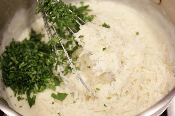 К молочной смеси добавить натертый сыр и зелень, снять с огня.