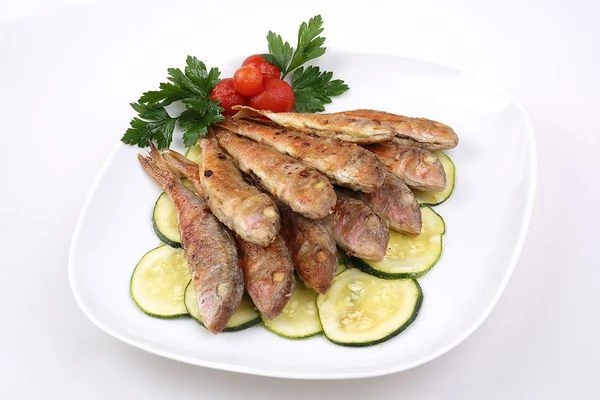 Маринованные кабачки выложить в один слой на тарелку, сверху выложить обжаренную рыбу, украсить зеленью и мини-помидорками.