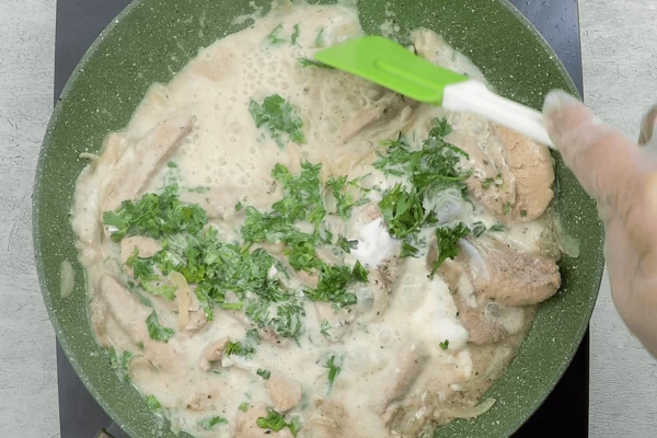 Добавить сметану, порубленный чеснок и петрушку. Накрыть крышкой и потушить 8-10 минут. В конце посолить, поперчить по вкусу.