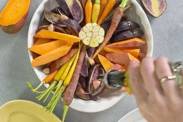 Головку чеснока разрезать пополам, выложить на овощи. Все посолить и полить оливковым маслом. Запекать при 180 градусах в течение 35 минут. 
