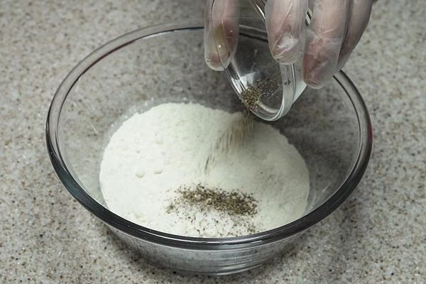  В глубокой чашке смешать половину муки, соль, перец. 