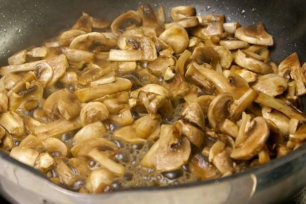 Обжарить на разогретой с оливковым маслом сковороде нарезанные грибы и репчатый лук.