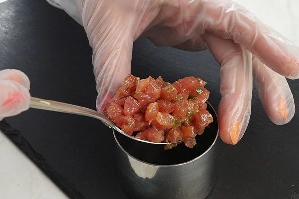 С помощью кулинарного кольца выложить замаринованного тунца на тарелку.