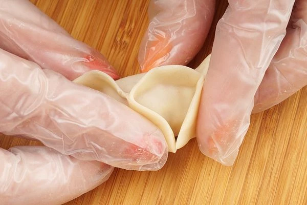 Смочить край теста водой, соединить тесто в центре, затем сложить бока. Залепить с одной стороны "ушко".