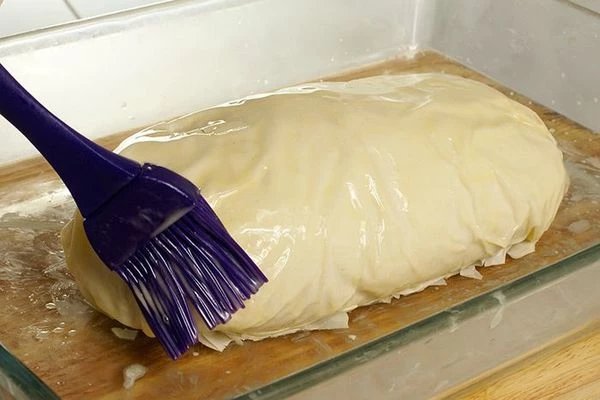 Завернуть тесто конвертиком, сверху смазать еще раз сливочным маслом. Поставить в разогретую до 220С духовку на 15-20 минут, выпекать до золотистого цвета корочки.