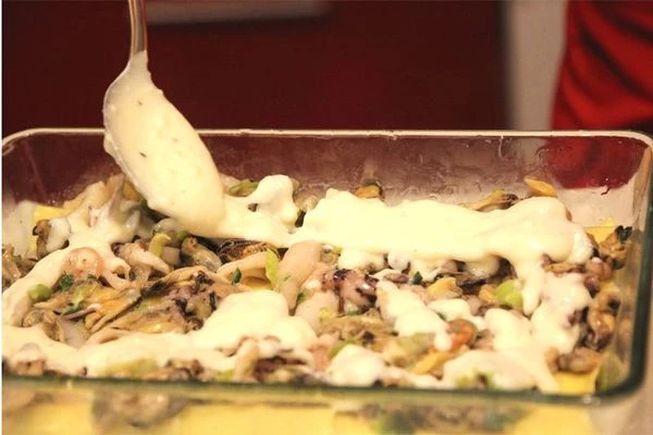 Приступаем к формированию лазаньи. В  жаропрочную форму с высокими бортами выложите два-три листа лазаньи слегка внахлест, чтобы закрыть дно. Далее тонким слоем уложите морепродукты, залейте  соусом Бешамель и уложите слой нарезанной пластинками Моцареллы. Важно! Если вы любите более плотную лазанью, добавляйте тертый Пармиджано Реджано или Грана Падана вместо Моцареллы.