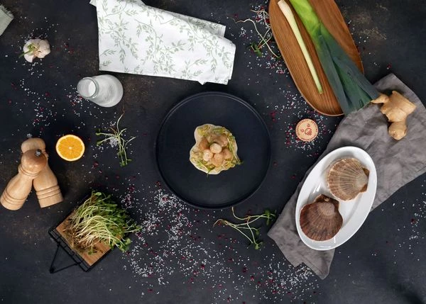 В тарелку для подачи выложить лук порей, на него гребешки. Полить соусом. Оформить микрозеленью. Приятного аппетита!