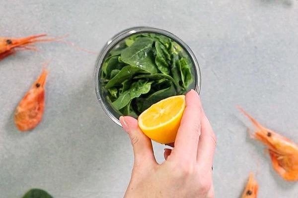 Лимон вымыть, снять цедру с ¼ части, разрезать пополам, выдавить сок из  1 половинки.
Шпинат вымыть, обсушить, удалить черешки. В чашу блендера выложить шпинат, влить растительное масло, сок лимона, добавить половину цедры лимона и щепотку сахара, измельчить.
