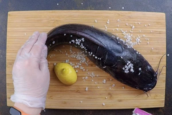 Рыбу разморозить естественным способом на нижней полке холодильника. Натереть солью и лимоном, чтобы проще было смыть естественную слизь. Оставить минут на 15.