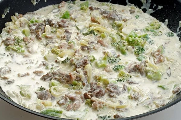 Затем к мясу добавить нарезанную крупным кубиком брокколи и сливки. Посолить, поперчить по вкусу.  Выпарить сливки примерно в половину.