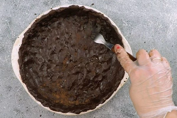 В форму для выпечки выложить промасленный пергамент (по диаметру дна), распределить тесто тонким слоем, делая бортики. Поставить в разогретую до 180С духовку на 25-30 минут.