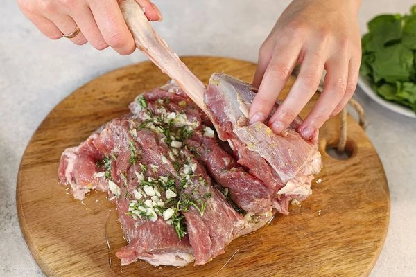 На мякоть выложить зачищенную косточку, свернуть ножку в рулет так, чтобы начинка оказалась внутри. Обвязать ножку кулинарным шпагатом. Обмазать оливковым маслом, положить на решетку.