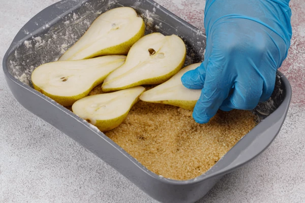 Груши разрезать вдоль пополам и уложить сверху на сахар.