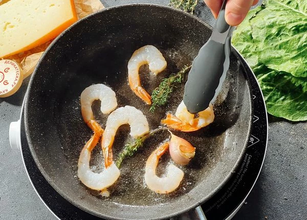 В большой сковороде разогреть оливковое масло, добавить чеснок веточку тимьяна и обжарить его пару минут до появления аромата. Добавить креветки в сковороду с оливковым маслом и обжарить их до румяной корочки, примерно по 2-3 минуты с каждой стороны. Посолить и поперчить по вкусу. Снять со сковороды.