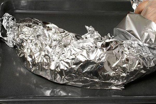 Завернуть всю тушку осетра в фольгу, выложить на смазанный противень. Запекать в разогретой до 200С духовке 25 минут, затем разрезать фольгу сверху и запечь без фольги еще 20 минут.