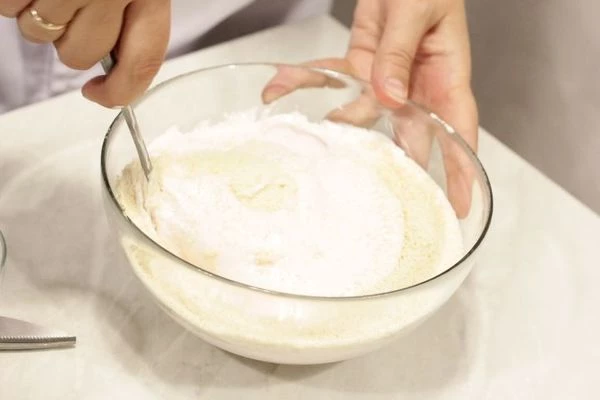 В глубокой миске аккуратно, чтобы не осели белки, смешайте миндальную муку и взбитый белок.