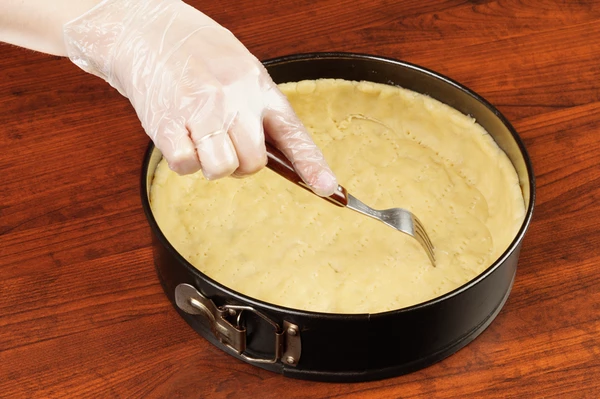 Когда тесто "отдохнет", распределить его по форме для запекания, сделав высокие бортики. Наколоть по всему периметру вилкой.