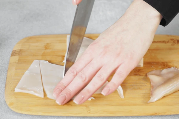 Кальмар разморозить на нижней полке холодильника, очистить от пленок, нарезать треугольниками.