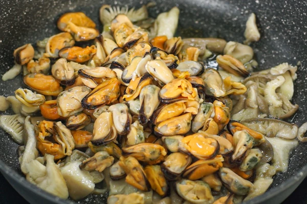 Вешенки вымыть, обсушить, нарезать. Мидии разморозить на нижней полке холодильника, очистить от “бороды”, промыть и обсушить на салфетке.
В сковороду налить оливковое масло, обжарить вешенки, затем мидии, посолить, поперчить.
