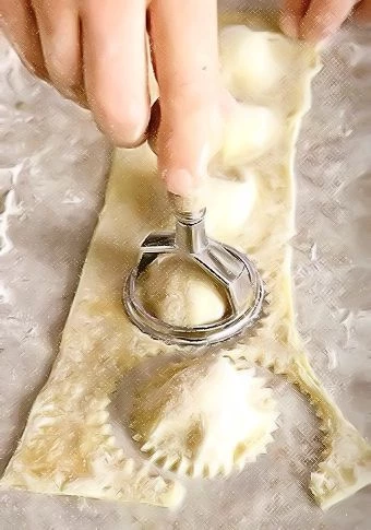 Вырежьте равиоли. Удобнее всего это делать с помощью специального ножа, но подойдет и обычный нож, можно с зубчатым лезвием - им можно просто разрезать тесто на квадратики с начинкой в центре.