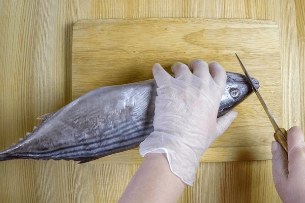 Хорошо замороженную рыбу промыть под холодной водой, обсушить бумажным полотенцем. Отрезать острую часть головы (для того, чтобы удобнее было строгать филе и рыба не скользила по доске).