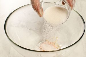 В глубокую чашку отделите яичный желток, добавьте сахар-песок, ванильный сахар