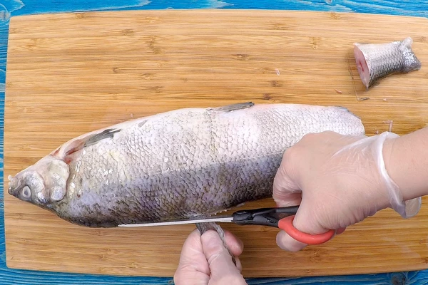 Рыбу разморозить естественным способом на нижней полке холодильника, очистить от чешуи. Срезать плавники.
